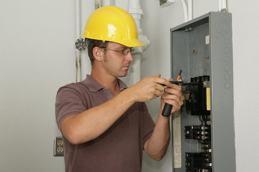 An electrician working on an industrial breaker panel. Model is an actual electrician performing all work to industry codes and safety standards.